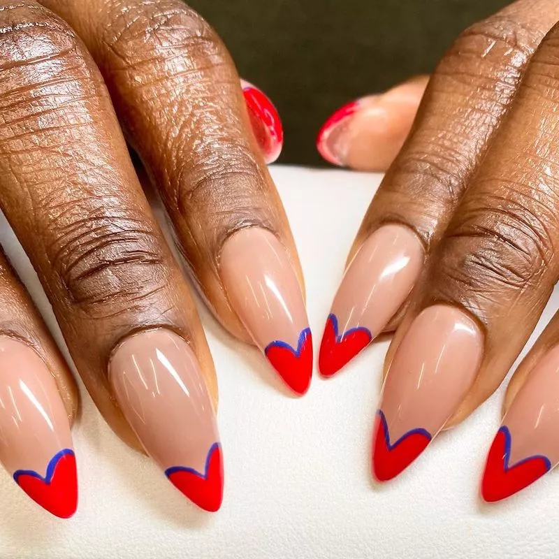 Neutral nails with red heart tips with blue outline