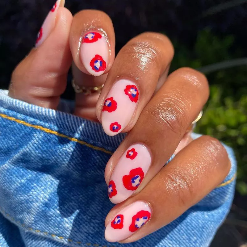 Peachy neutral nails with red and blue poppy design