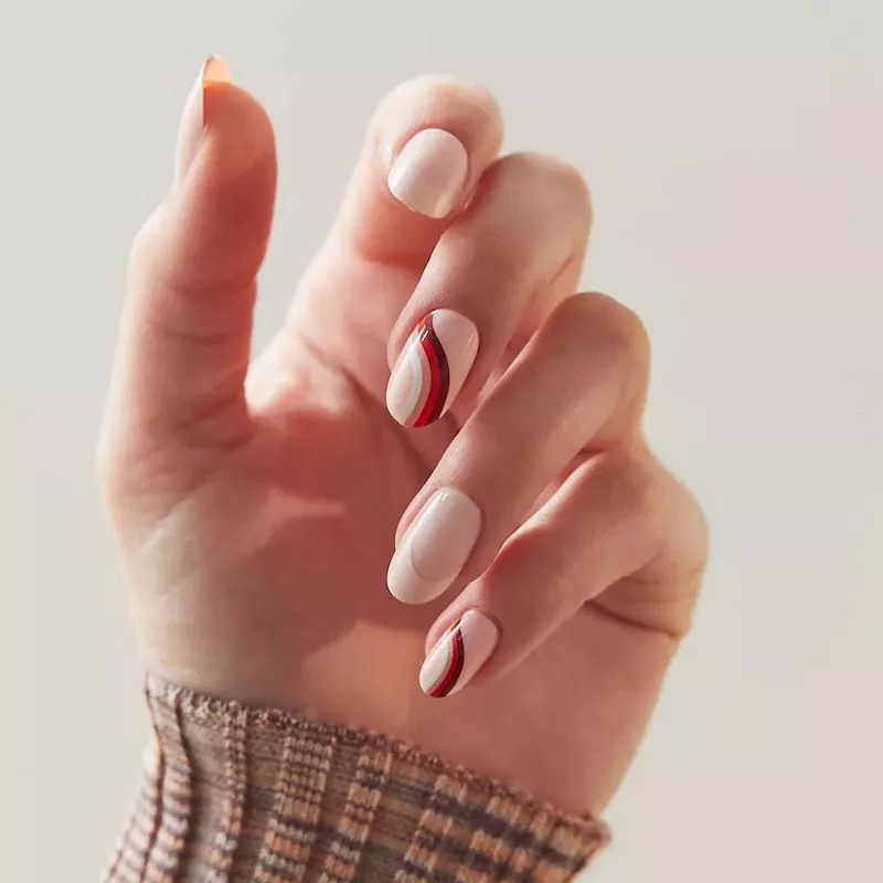 Manicure with neutral base and red and brown wavy design