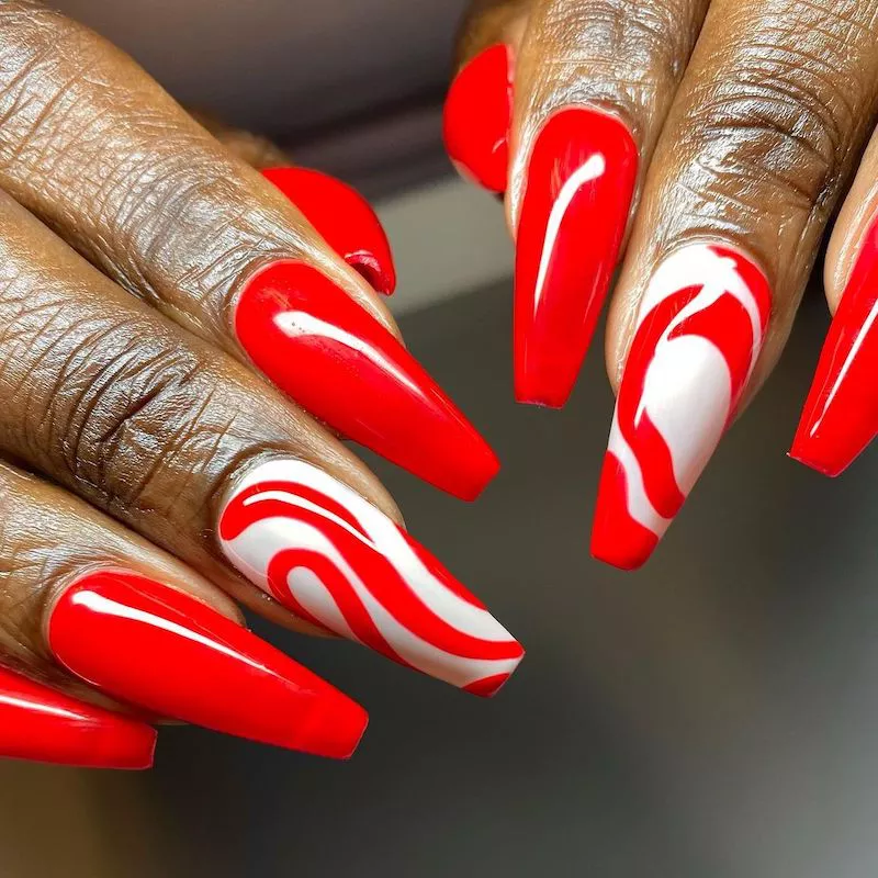 Acrylic red nails with white swirl accents
