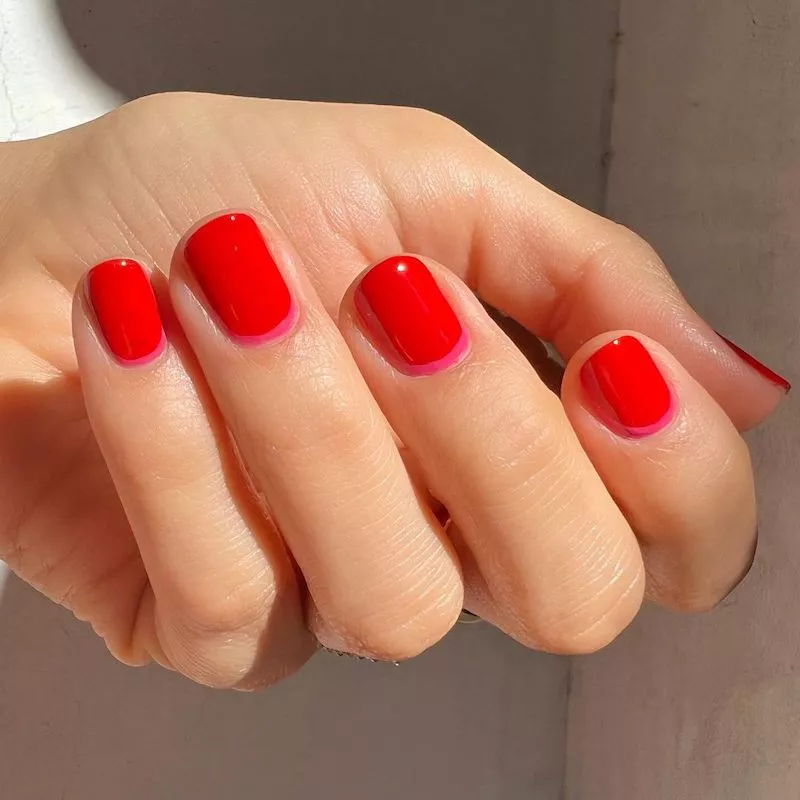 Red manicure with subtle dark pink cuticle accent