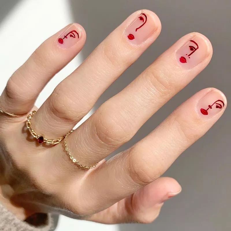 Manicure with clear base and abstract red face designs