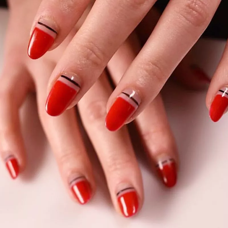 Glossy red manicure with negative space base and thin black stripe accent