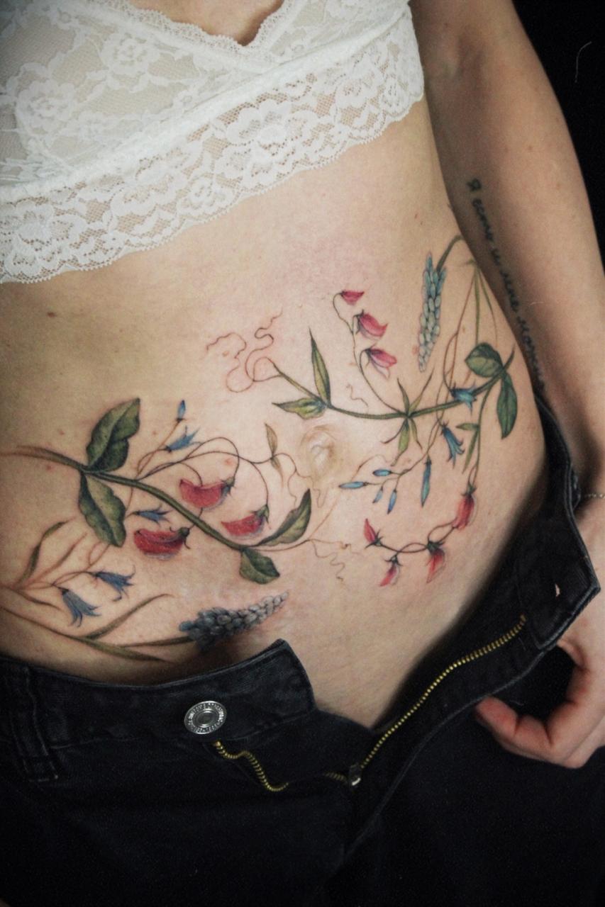 Ботаническая татуировка на животе у девушки