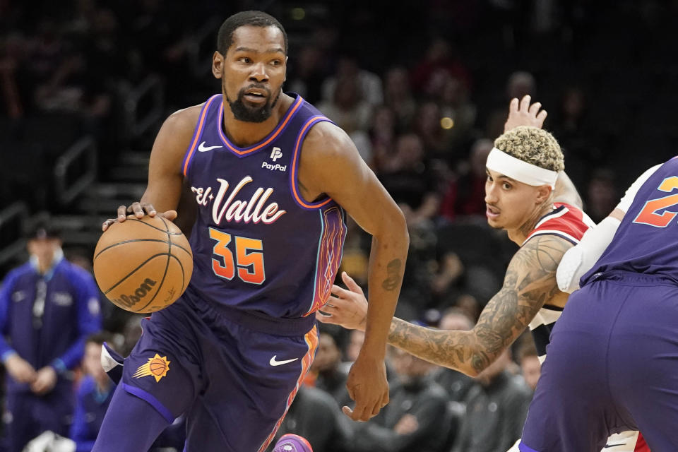 Phoenix Suns forward Kevin Durant dribbles around Washington Wizards forward Kyle Kuzma during a game in Phoenix on Dec. 17, 2023. (AP Photo/Darryl Webb)