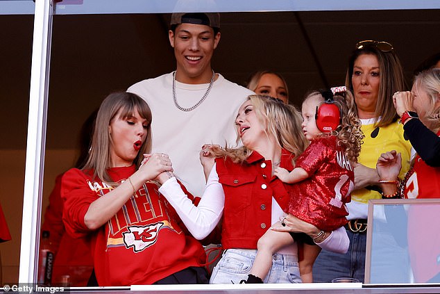 Taylor Swift and Brittany Mahomes do a handshake in their luxury box at Arrowhead Stadium