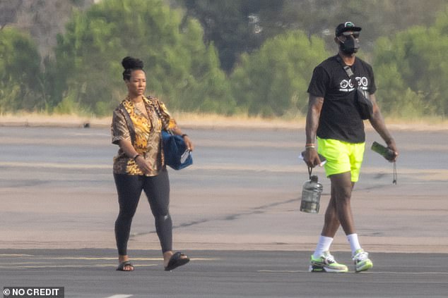 En route: LeBron changed into a black T-shirt, fluorescent yellow shorts, matching sneakers and a black cap as he prepared to board a private jet, presumably back to Los Angeles