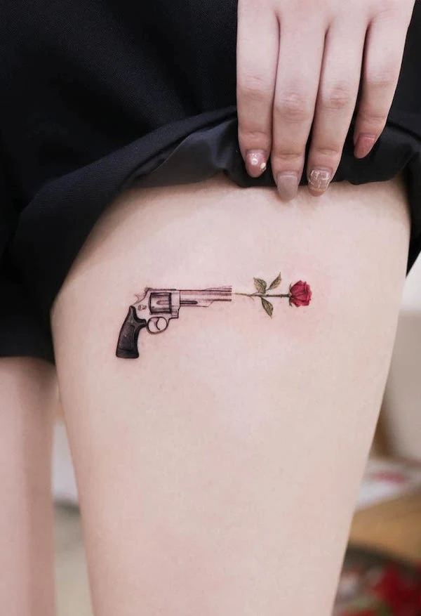 Gun and rose thigh tattoo by @tattoo.haneu