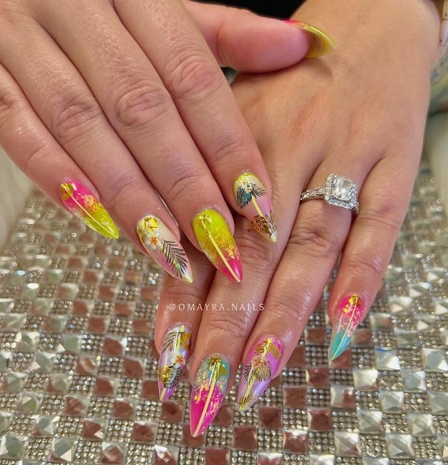 A woman's long stiletto nails with combinations like pink and yellow, purple and pink, and pink and blue that has coconut trees and tropical flowers in chunky glitter and gold flecks