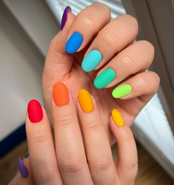 A closeup of a woman's short nails with vibrant matte colors