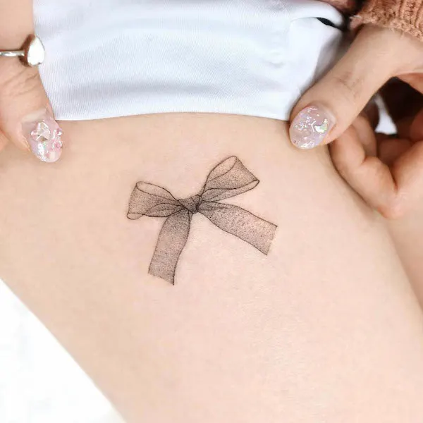 Small bow thigh tattoo by @palette.tt_