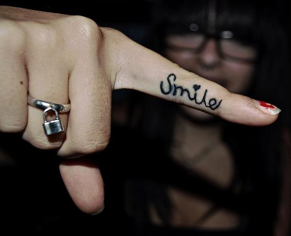 Word Smile lettering tattoo with a love symbol