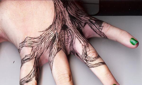 Tree roots tattoo spreading from hand to fingers