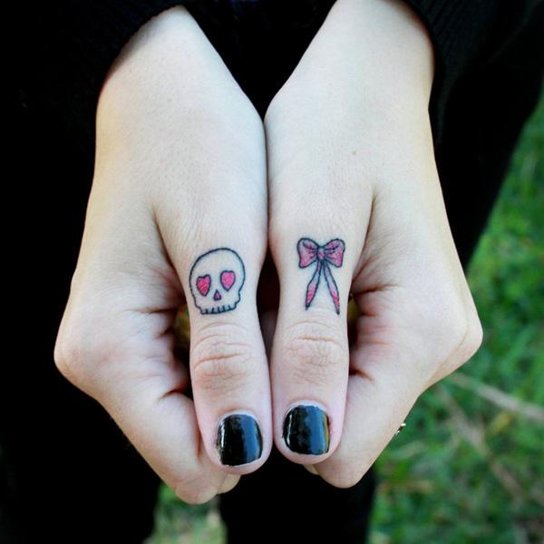 Skull and Bow tattoos on two thumbs