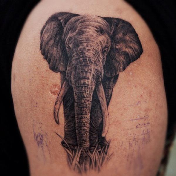 A black elephant on grass thigh tattoo