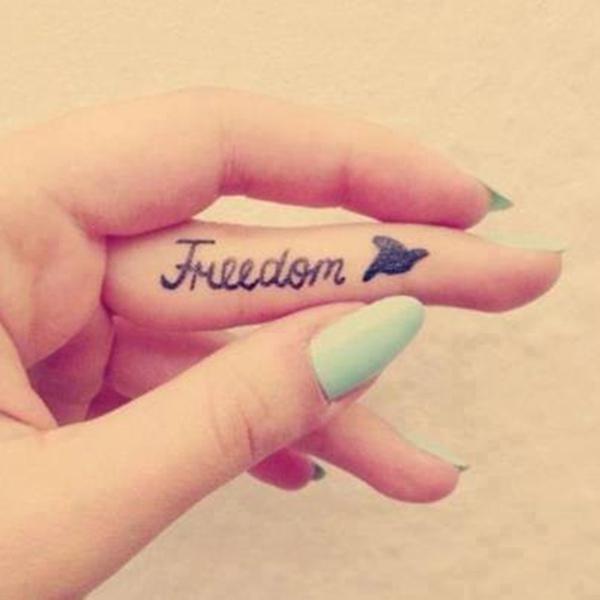 Word Freedom and bird finger tattoo