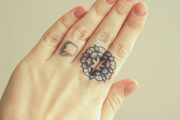 Circular mandala tattoo on two fingers