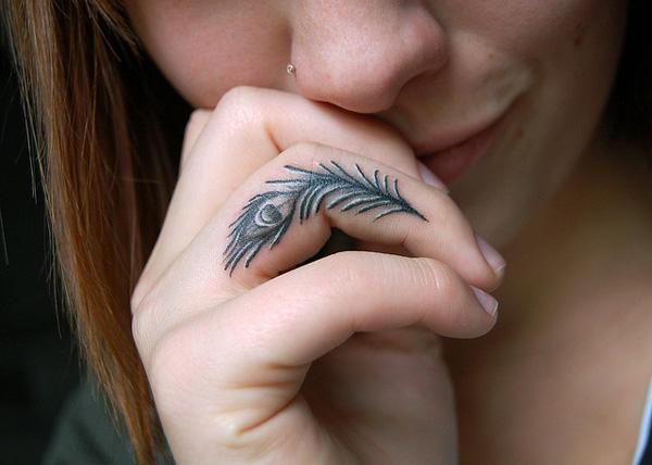Peacock feather with eye tattoo on ring finger