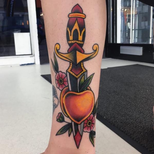 A dagger throug a peach tattoo on lower leg