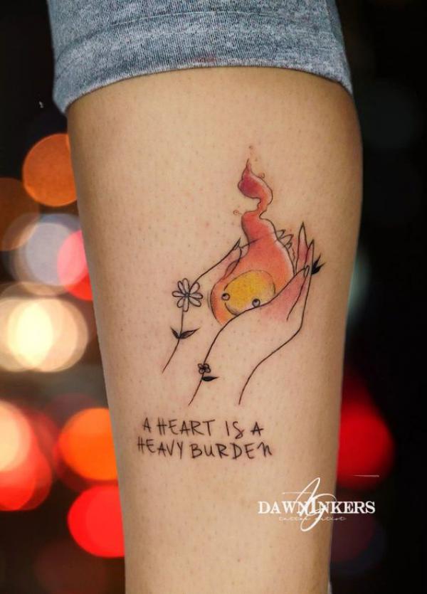 A hand holding Calcifer tattoo with quote A heart is heavy burden