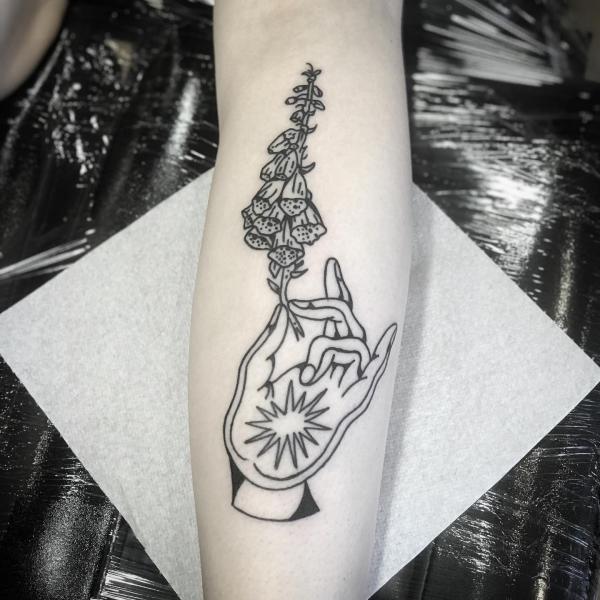 A hand holding foxglove tattoo