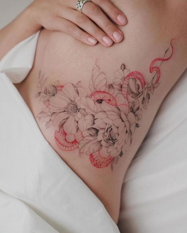 A red snake interwined with flowers side boob tattoo