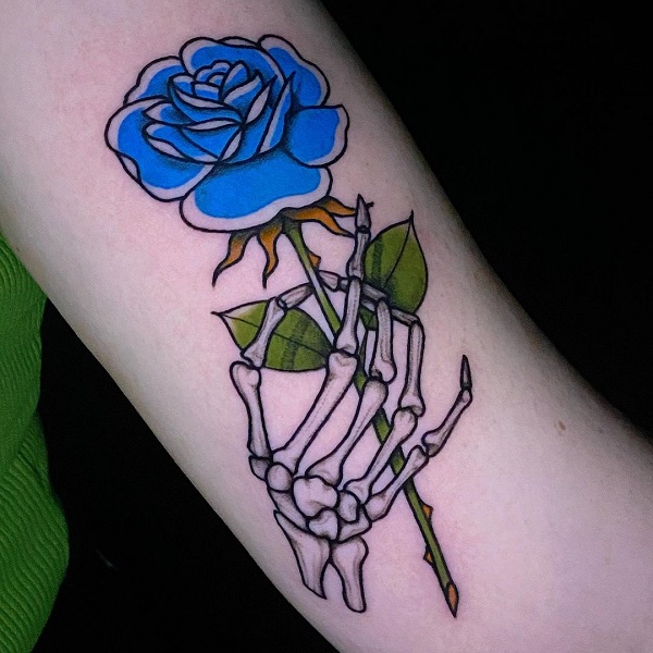 A skeleton hand holding a blue rose