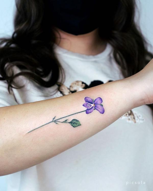 A stem of violet flower on forearm
