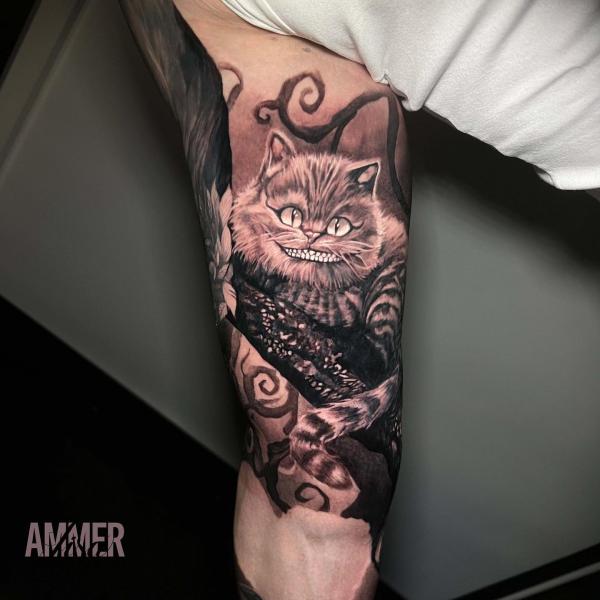 Black and grey Cheshire Cat bicep tattoo