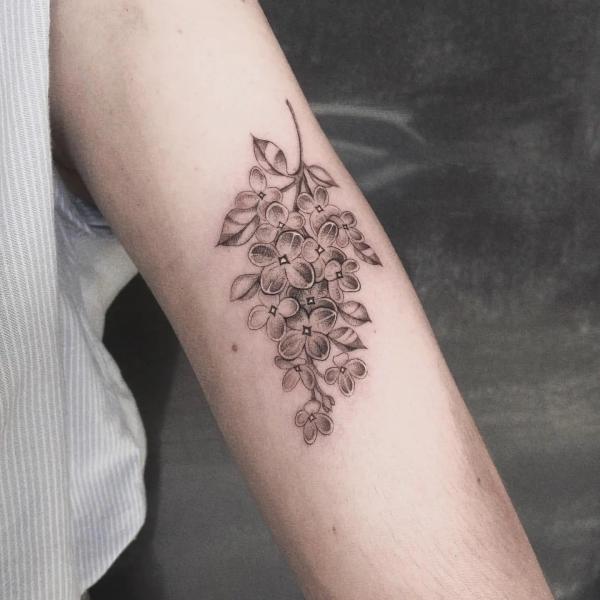 Black and grey lilac tattoo on upper arm