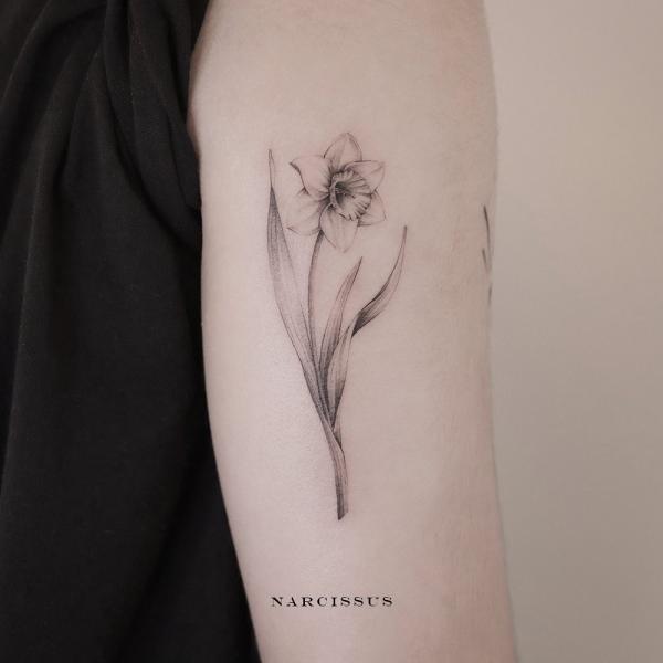 Black and grey narcissus tattoo on upper arm