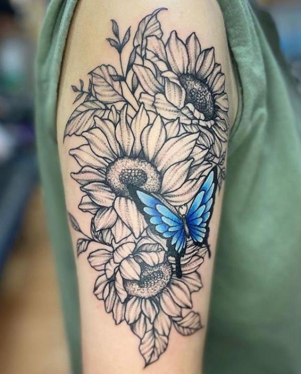 Black and grey sunflower and blue butterfly tattoo on upper arm