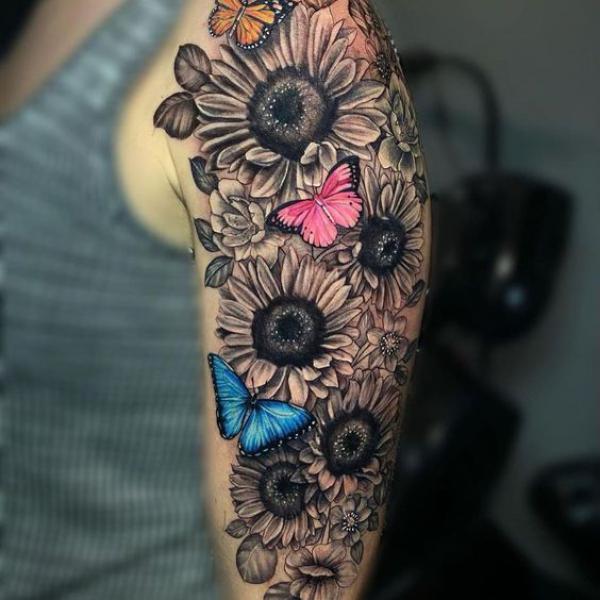Black and grey sunflowers and colorful butterflies tattoo on upper arm