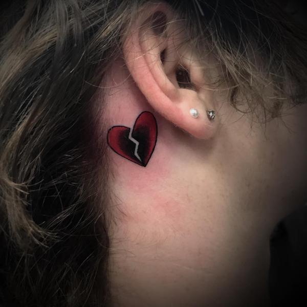 Black and red broken heart tattoo behind the ear