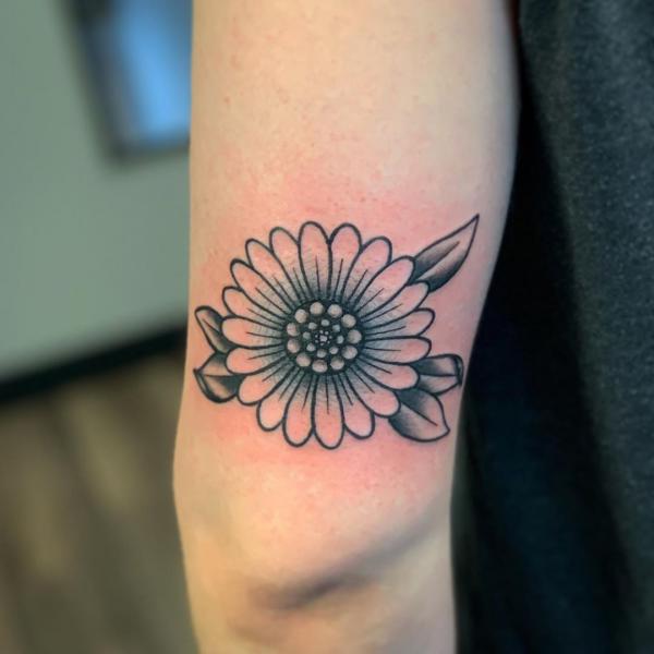 Black and white daisy tattoo above elbow