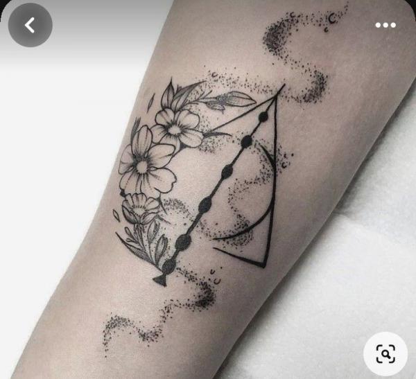 Black and white deathly hallows with flowers tattoo