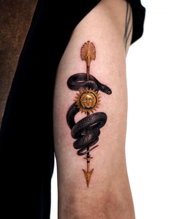 Black snake and golden arrow upper arm tattoo