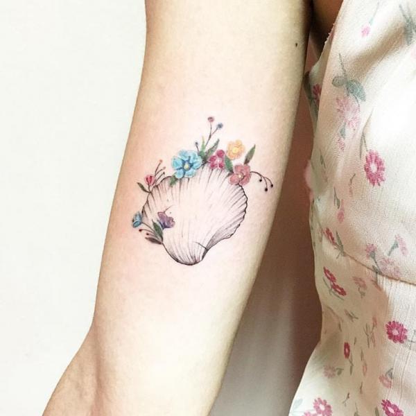 Cute shell with colored flowers upper arm tattoo