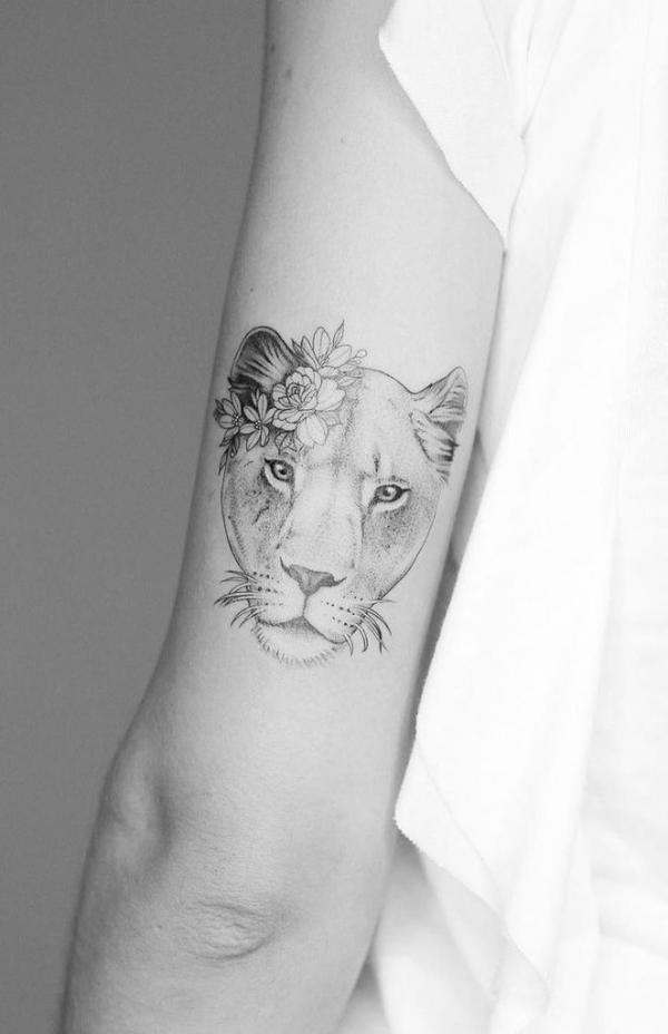 Dainty lioness head with flower back of arm tattoo