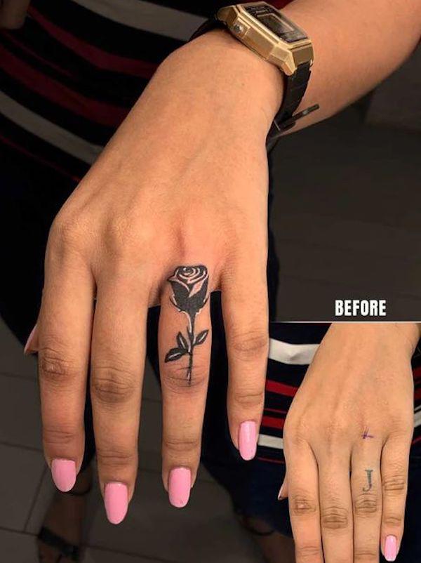 Elegant black rose cover up tattoo on ring finger