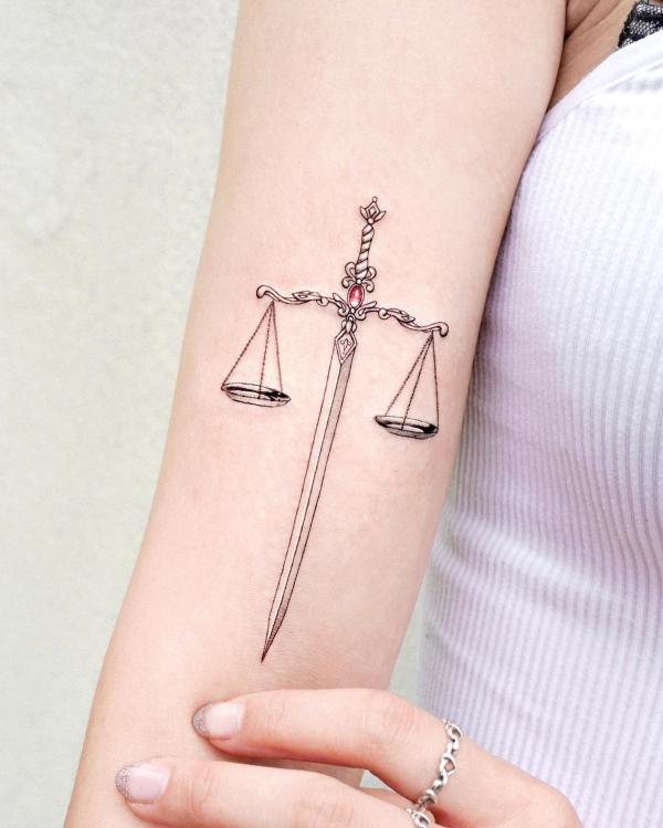 Feminine Libra sword tattoo on upper arm 1