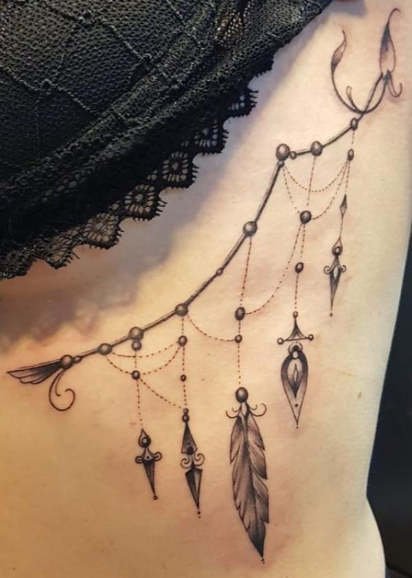 Feminine feather and jewelry pendant side boob tattoo