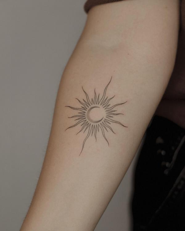 Fine line sun and moon tattoo on forearm