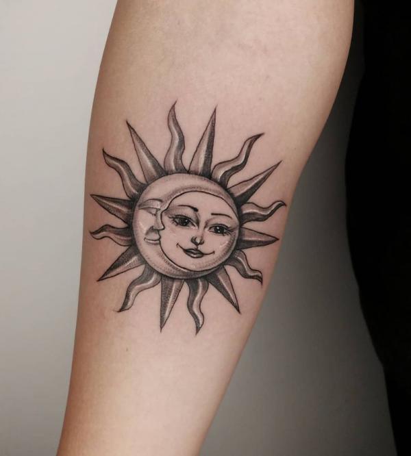 Forearm sun and moon face tattoo