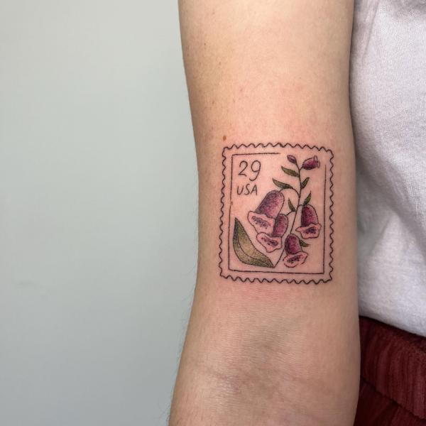 Foxglove stamp tattoo above inner elbow