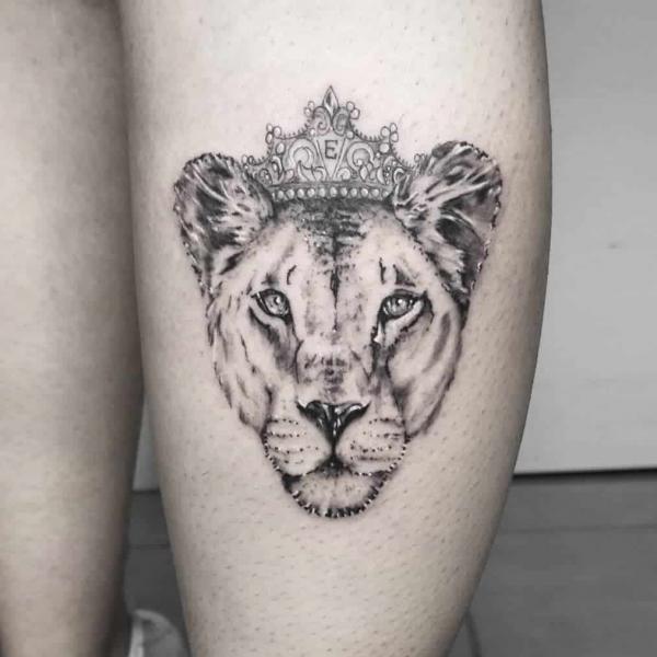 Lioness head with crown thigh tattoo