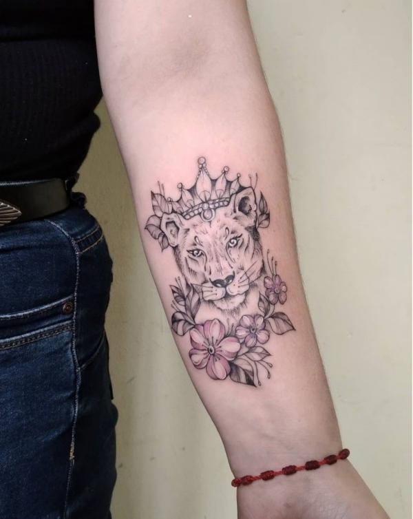 Lioness with crown with flower tattoo on inner forearm