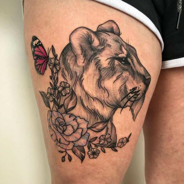 Lioness with flowers and butterfly tattoo on thigh