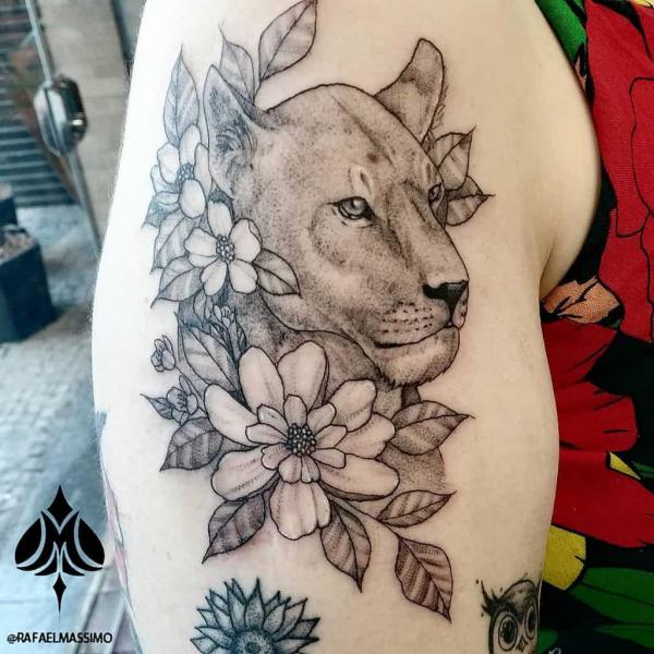 Lioness with flowers upper arm tattoo black and grey