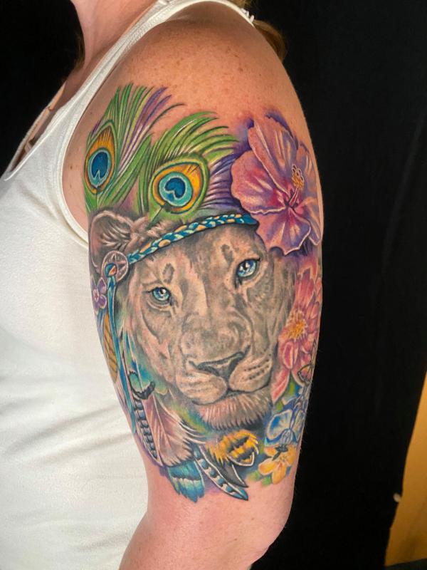 Lioness with hibiscus and peacock feather tattoo